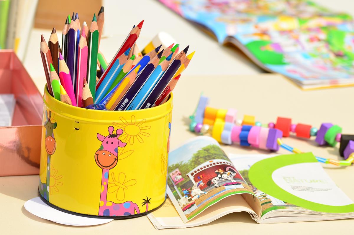 Graphic: colored pencils in a yellow can with a giraffe on it, children's book and toy.