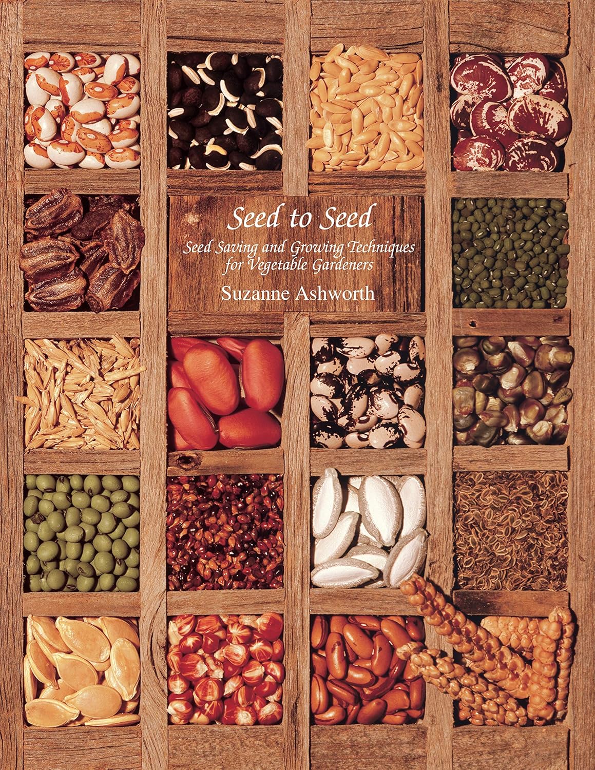 A wooden tray holds various colorful seeds organized in compartments, showcasing diversity. Text reads "Seed to Seed" by Suzanne Ashworth. Warm, earthy tones.